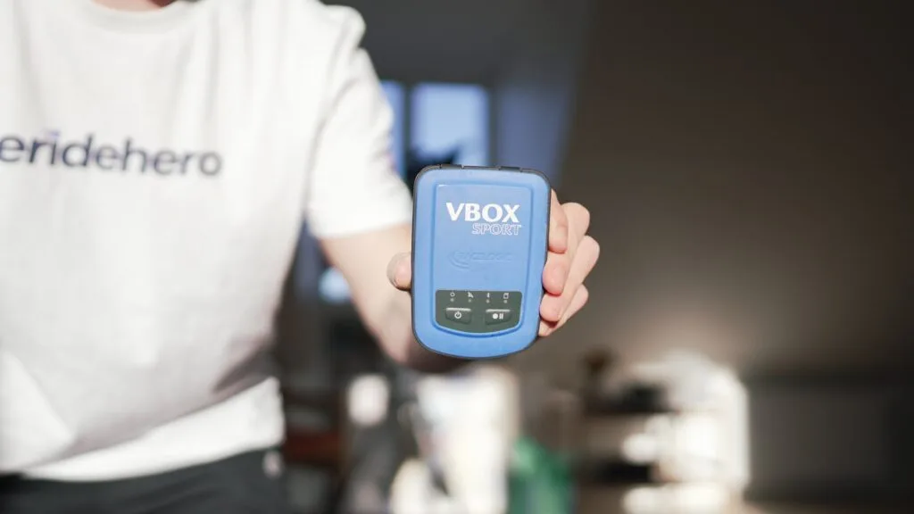 Closeup of the VBox Sport performance logger with a blurred background and a white t-shirt with an ERideHero logo on