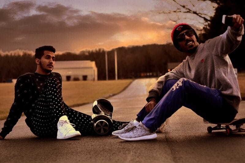 people taking selfie with a hoverboard and skateboard