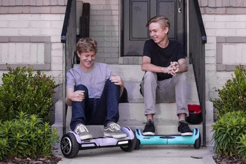two kids sitting on porch smiling with their hoverboards