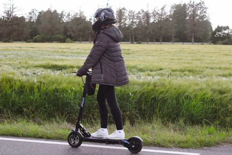 Girl riding an electric scooter using a motorcycle helmet