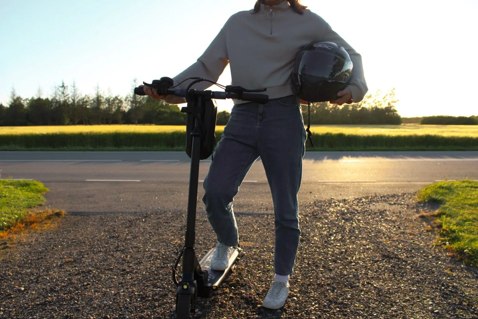 girl with her electric scooter helmet in the sunset