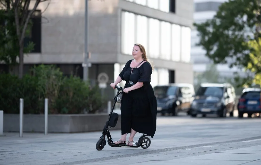 happy overweight woman riding on an electric scooter through the city