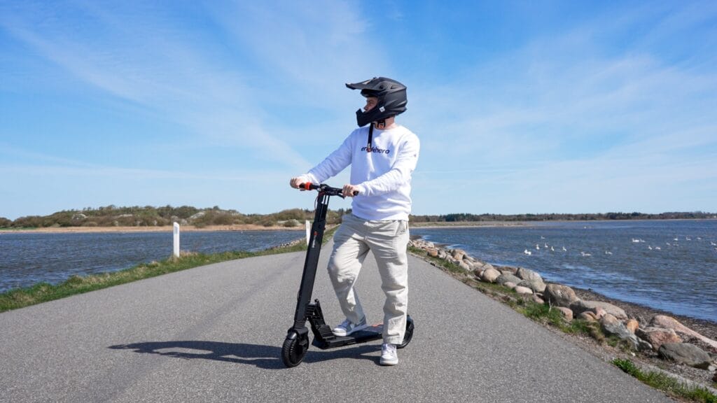 Man with the Turboant V8 electric scooter on the road with scenic water in the background