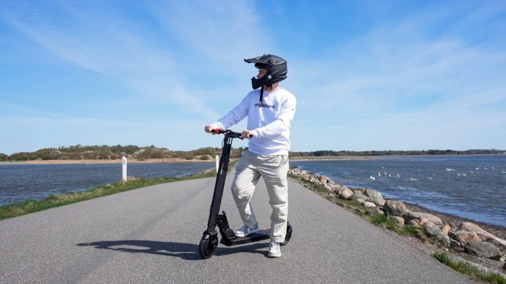 Man with the Turboant V8 electric scooter on the road with scenic water in the background