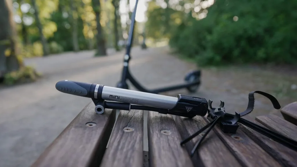 Close-up of the Topeak Mini Morph portable air pump with an electric scooter in the background