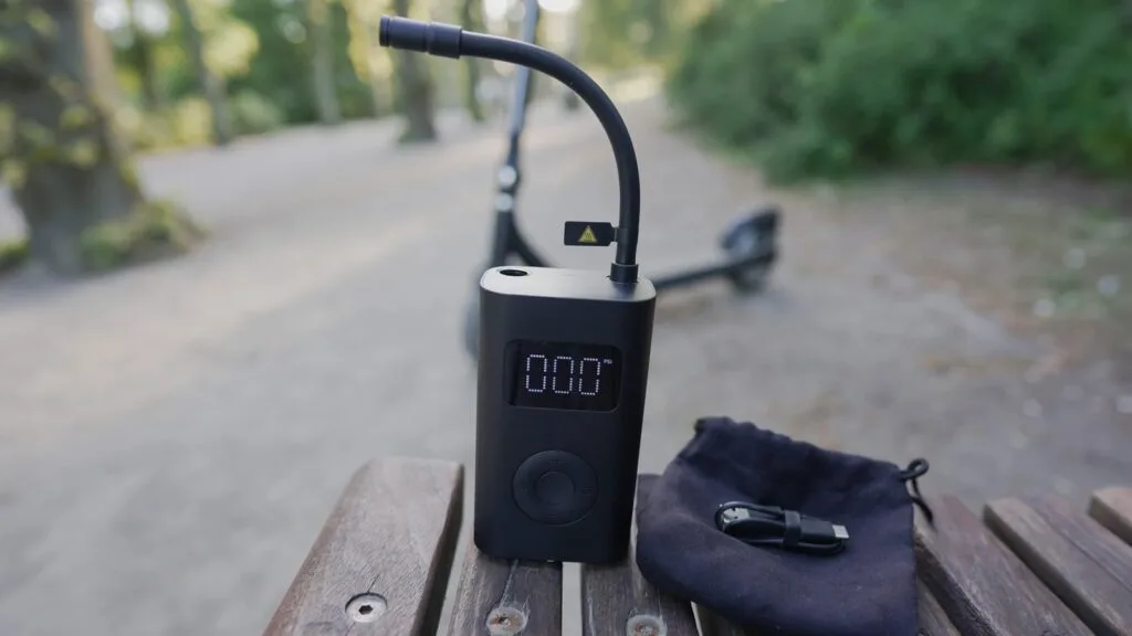 Close-up of the Xiaomi 1S electric air compressor with an electric scooter in the background