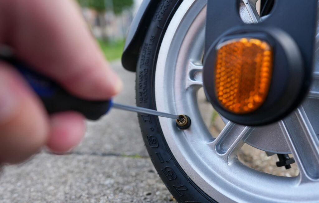 Electric scooter tire deflation using a screwdriver in the nozzle