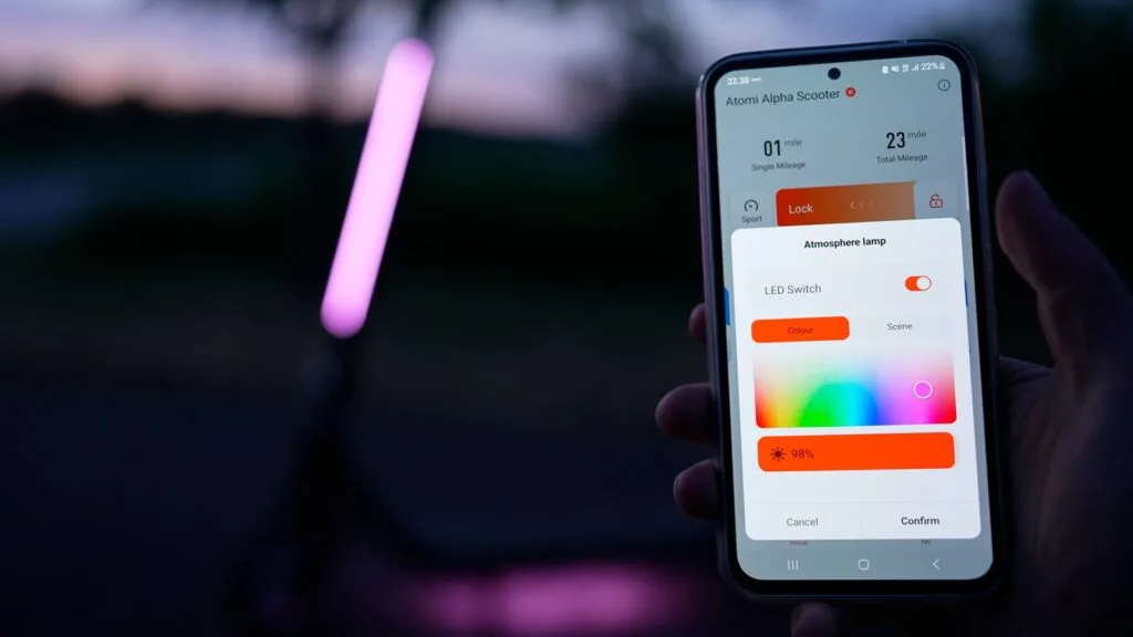 showcasing the smartphone app for the Atomi Alpha with the electric scooter in the background