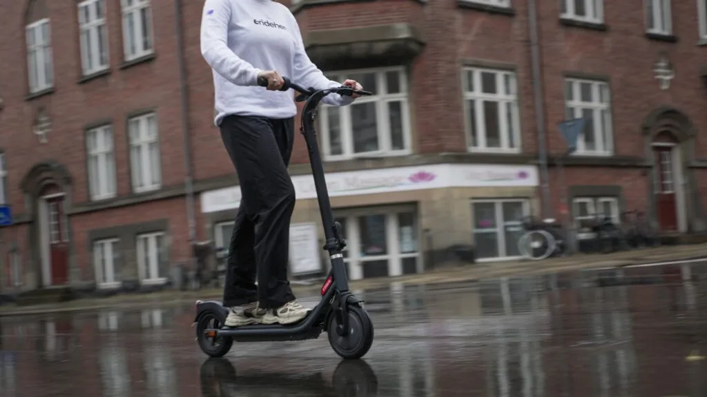 Riding an electrics cooter in the rain on a wet road