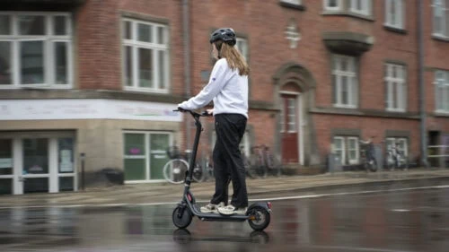 Girl from ERideHero riding an electric scooter in the rain wearing a helmet to comply with local laws
