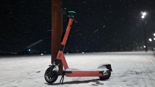Electric scooter from the rental company Voi outside in the snow at night with street lights